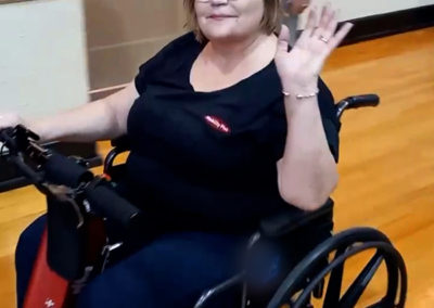 An image of a woman at a care facility testing the EZRide unit on a manual wheelchair during a demo day