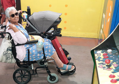 An image of EZRide owner Ms. Maya in her wheelchair with the EZRide connected. She's parked next to a stroller