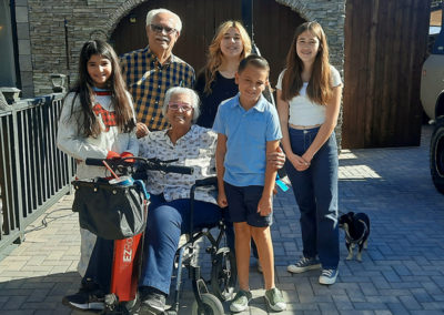 An image of EZRide owner Ms Maya with her wheelchair and unit in a family photo with husband and grandchildren